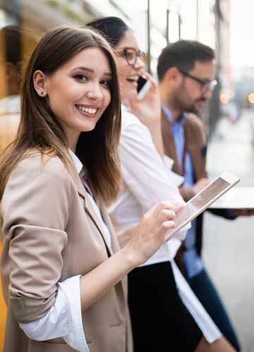 people standing outside using their cell phones and tablets, with woman smiling at camera